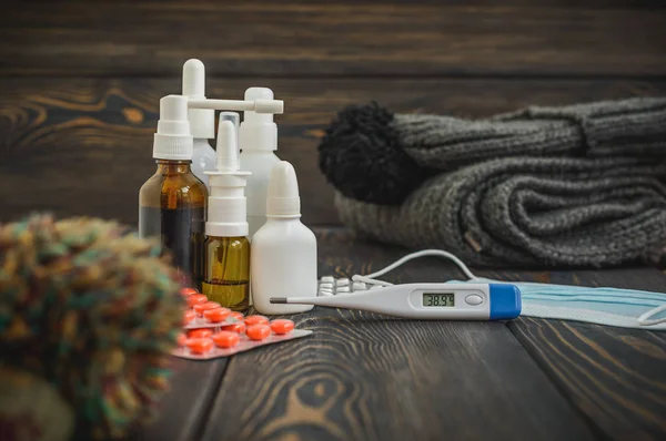Comprimidos, nariz cai um tratamento frio, gripe escorrendo sobre a mesa com um termômetro eletrônico — Fotografia de Stock