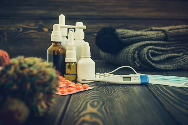Comprimidos, nariz cai um tratamento frio, gripe escorrendo sobre a mesa com um termômetro eletrônico, imagem tonificada — Fotografia de Stock