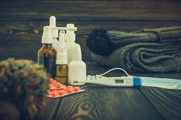 Comprimidos, nariz cai um tratamento frio, gripe escorrendo sobre a mesa com um termômetro eletrônico, imagem tonificada — Fotografia de Stock