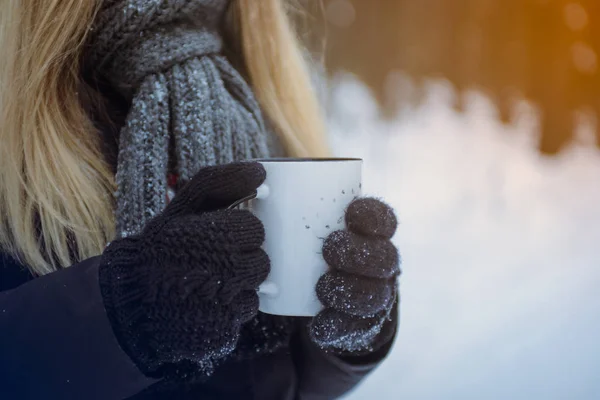 Mão luva mitene segurando uma caneca de viagem. WInter floresta fundo nevado . Imagens De Bancos De Imagens