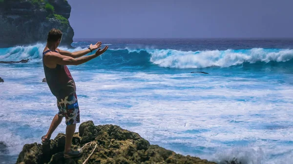 Man Provoke Ocean Waves na costa de Tembeling na ilha de Nusa Penida, Bali Indonesia — Fotografia de Stock