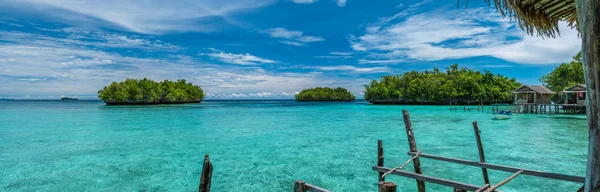 Piękny niebieski Lagoone z niektórych Bamboo Huts Kordiris Homestay, Palmtree w przód, Wyspa Gam, West papuaskie, Raja Ampat, Indonezja — Zdjęcie stockowe