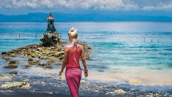 Kadınlar doğru tatlı bir tapınak Nusa Penida dramatik bulutların üzerinde Bali, Endonezya ile denizde tarafından Sahilde yürüyüş