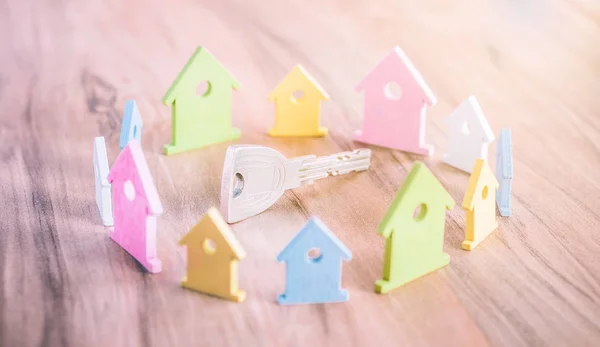 Silver Key på träytan omgiven av bor miniatyr symbol av hus i olika färger — Stockfoto