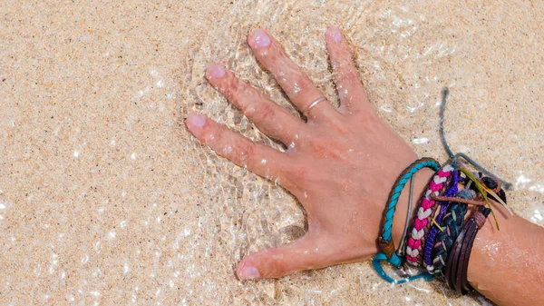 화려한 팔찌 Toching 젖은 모래 해변에서 여자 손 — 스톡 사진