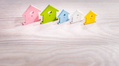Değişik renkli ev simgeler parlak ahşap yüzeyi satırında kalıyor