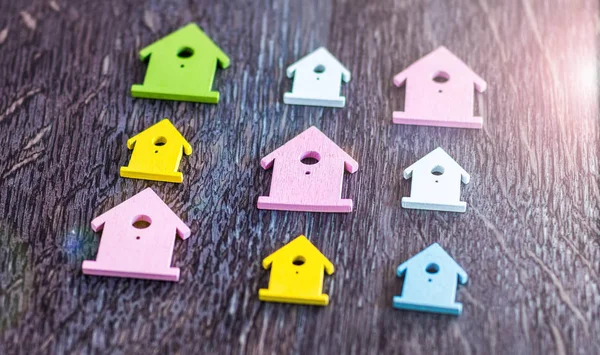 Símbolo em miniatura de várias casas coloridas que colocam simétrica na superfície de madeira escura — Fotografia de Stock