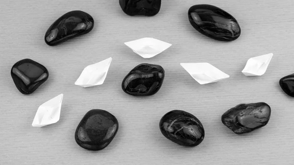 Vitt papper båtar i sigle fil mellan abstrakt rock stenar. Svart och vitt — Stockfoto