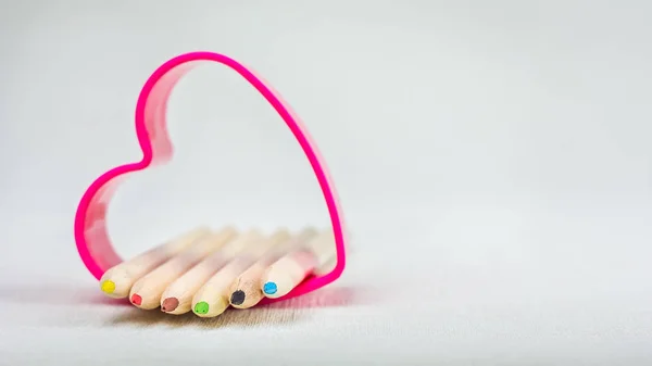 Lápices de color colocados en el símbolo del corazón rojo y representan el amor al dibujo de la creatividad — Foto de Stock