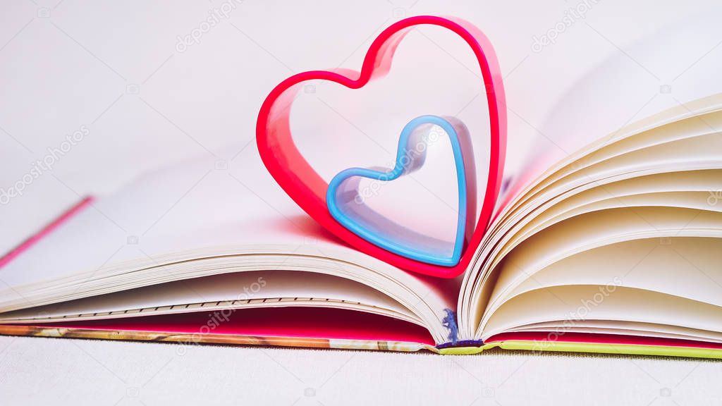 Red and blue hearts over diary book on white table