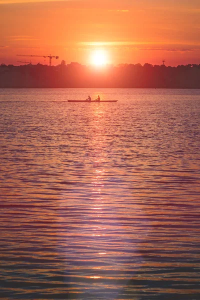 Σιλουέτα της ομάδας εργάζονται συχνά δύο νεαρούς άνδρες σε μια βάρκα με κουπιά στο ηλιοβασίλεμα — Φωτογραφία Αρχείου
