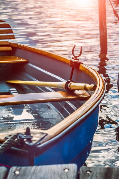 Wooden pleasure rowboat at the pier of a lake at evening sunset light — Stock Photo, Image