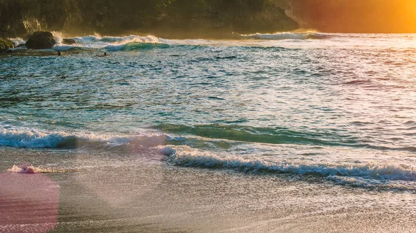 Místní děti surfovat na vlnách v Sunset světle, krásná Crystal Bay, Nusa Penida Bali — Stock fotografie