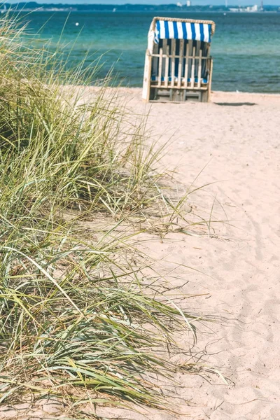 Sand klit med græs og blå farvede tagstole på sandstrand i baggrunden. Travunde. Tyskland - Stock-foto