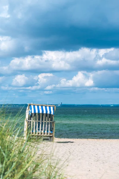 Nubes lluviosas sobre la playa con sillas cubiertas de color azul en Travemunde. Alemania — Foto de Stock