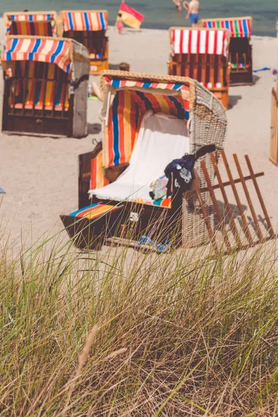 Оренда червоний стілець дахівками на піщаному пляжі в Травемюнде, Північна Німеччина. Суха трава на передньому плані — стокове фото