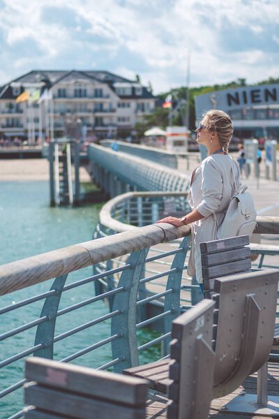 Woomen on pier near beach with roofed wicker chairs in Travemuende at the Baltic Sea. Travepromenade in Travemunde, a borough of Lubeck, Germany