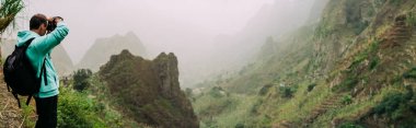 Xo-Xo vadiden şaşırtıcı sarp dağlık arazi yemyeşil Kanyon Vadisi yolu ile bir fotoğraf çekmek için kamera tutan gezgin. Santo Antao Adası, Cape Verde
