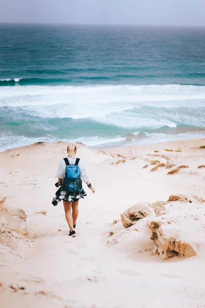 여자는 모래 언덕을 내려가는 가방을 들고 외로운 해변을 향해 걸어 갑니다. 사 오 비센테 카보베르데 — 스톡 사진