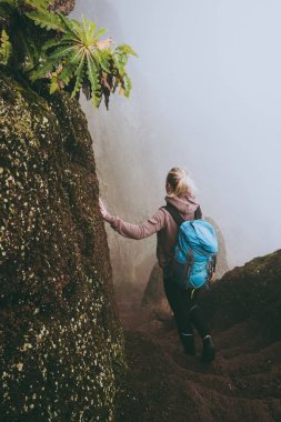 Santo Antao. Cape Verde. Kız mavi sırt çantası ile yürüyüş sisli dağlar Rock'da dik yamaç aşağı