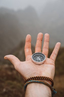 Bir pusula tutan el. Siluet arka plan anıtsal dağ oluşumu