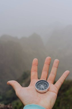 Adam palm holding pusula. Sisli dağlık manzara
