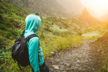 Yalnız seyahat Arnavut kaldırımlı trekking iz yeşil vadiye doğru yürüyen sırt çantası ile. Hoziron üzerinde güneş patlamaları. Santo Antao Adası, Cape Verde