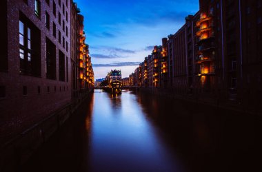 Depo bölgesi - Speicherstadt mavi saate. Alacakaranlık Hamburg turizm landmark. Fener ışık lamba Wandrahmsfleet görünümünde. Yer Hamburg liman içinde Hafencity çeyrek içinde yer alır