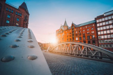Hamburg, Almanya 'da Speicherstad eyaletinde tarihi depolarda demir kemerli köprüler. Arka planda parlayan güneş ışığı