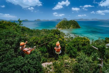 Güneşli bir günde turistle Las Cabanas Sahili 'nde beyaz bulutlu bir halatla kaymak. El Nido, Palawan, Filipinler