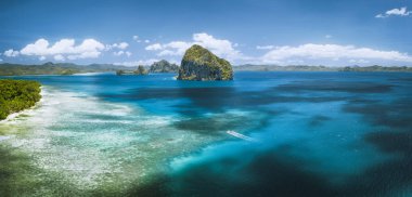 El Nido, Palawan, Filipinler. Panoramik hava manzaralı açık denizde yalnız bir turist teknesi ve okyanusta bekleyen egzotik bir Pinagbuyutan adası. Güneydoğu Asya Bacuit takımadaları