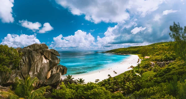 Panoramiczny widok pięknej plaży Grand Anse na wyspie La Digue na Seszelach. Niebieska laguna z białymi chmurami nad nami — Zdjęcie stockowe