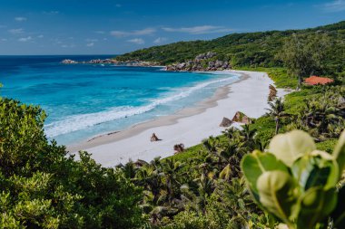 Seyşeller 'deki La Digue adasındaki Grand Anse plajı. Mavi okyanus gölü ve granit kayaları olan beyaz kumlu sahil.