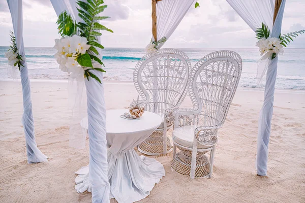 Decorated romantic wedding setting with table and chairs on sandy tropical beach with ocean and cloudy sky, Seychelles islands — Stock Photo, Image