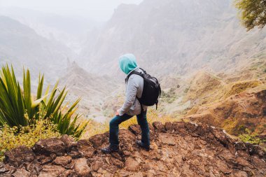 Santo Antao Adası, Cape Verde. Sırt çantalı gezgin taşlı yolda gerçek üstü Xo Xo vadisi ve dağ sırtı manzarasının tadını çıkarıyor.