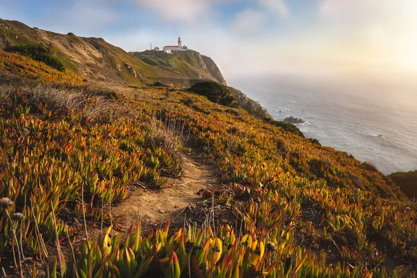 Sintra Portugal. Lighthouse on Cape Roca. Travel and hiking path lit by golden sunset light. Tourism landmark with beautiful coastline cliffs along atlantic ocean coast — 스톡 사진