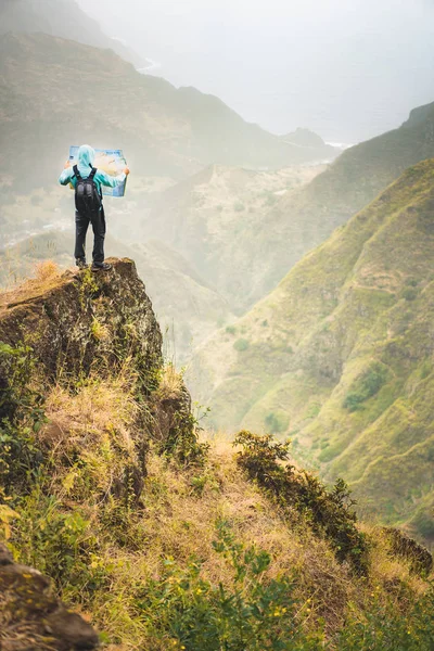 Один турист с картой острова, останавливающийся на скальном склоне перед великолепным панорамным видом на высокие горные хребты и пышные зеленые ванны. Санто-Антао-Кабо-Верде . — стоковое фото