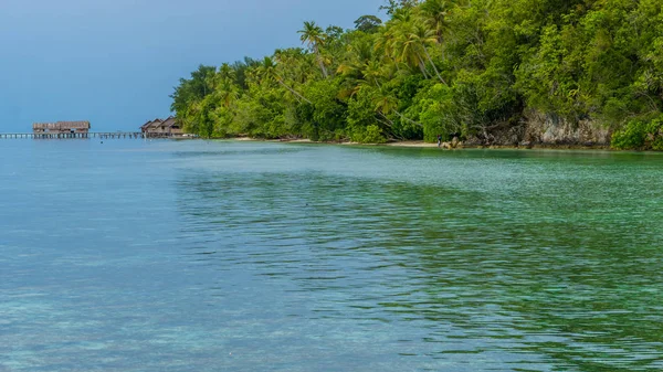 Bahía con corales submarinos en frente de la estación de buceo y casas de huéspedes en la isla de Kri, Raja Ampat, Indonesia, Papúa Occidental — Foto de Stock