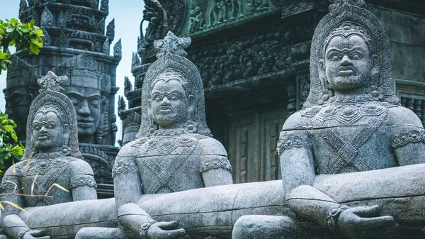 Skulptur de gente salvaje con caras extrañas. Antiguo templo con cara de piedra en el fondo — Foto de Stock
