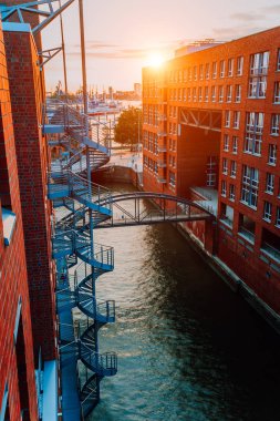 Dairesel merdiven, altın saat gün batımı ışık, Almanya Eski depo bölgesi Speicherstadt Hamburg'da kanal ve kırmızı tuğla binalar üzerinde köprü. Yukarıdan görüntülemek