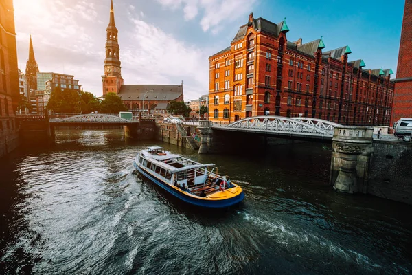 Barco de cruzeiro turístico em um canal com pontes no antigo distrito de armazém Speicherstadt em Hamburgo em luz do pôr do sol de hora dourada, Alemanha — Fotografia de Stock