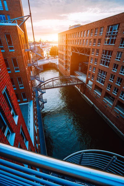 Escadaria de metal, ponte sobre o canal e edifícios de tijolos vermelhos no antigo distrito de armazéns Speicherstadt em Hamburgo em luz do pôr-do-sol de hora dourada, Alemanha. Vista de cima — Fotografia de Stock