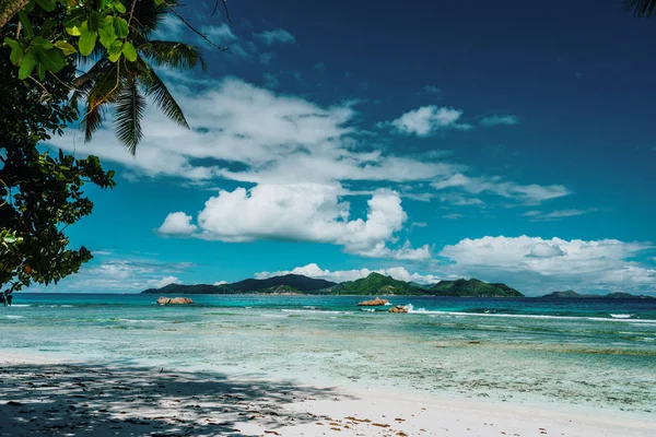 Anse Anse Závažná pláž za slunečného dne na ostrově La Digue na Seychelách. Praslinův ostrov v pozadí. Exotický ráj cestovní scenérie koncept — Stock fotografie