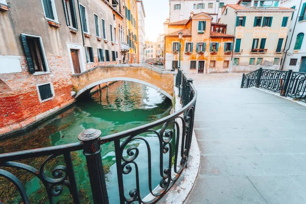 意大利威尼斯风景秀丽的运河，大桥和五彩斑斓的建筑物映衬着金色的落日光芒 — 图库照片
