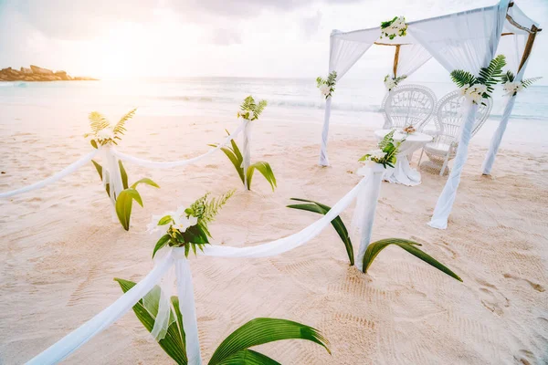 Оформление романтической свадьбы со столом и стульями на песчаном тропическом пляже при закате солнца, Сейшельские острова — стоковое фото
