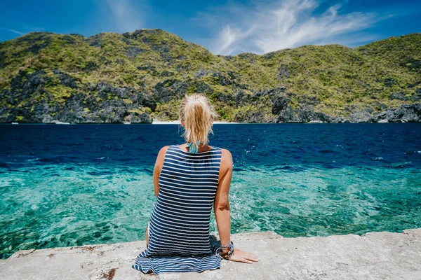 필리핀 팔 라완 의 C.El Nido 관광을 기대하며 섬에서 타피 우탄 해협을 즐기고 있는 마틴 록 부두에 앉아 있는 관광객 여성의 뒷모습 — 스톡 사진