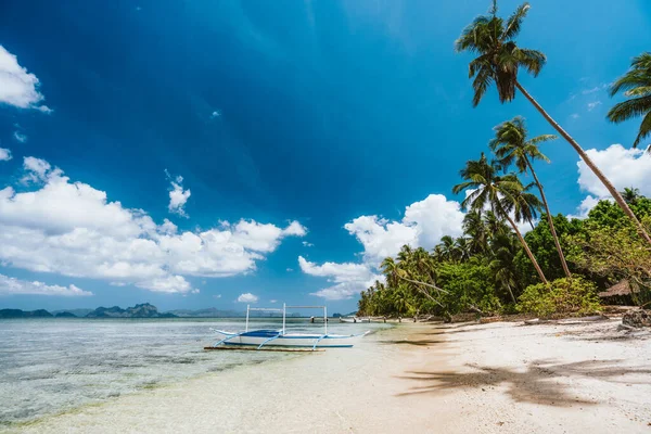 El Nido, Palawan, Filipinas. Playa de arena con palmeras, barco turístico y cielo azul — Foto de Stock