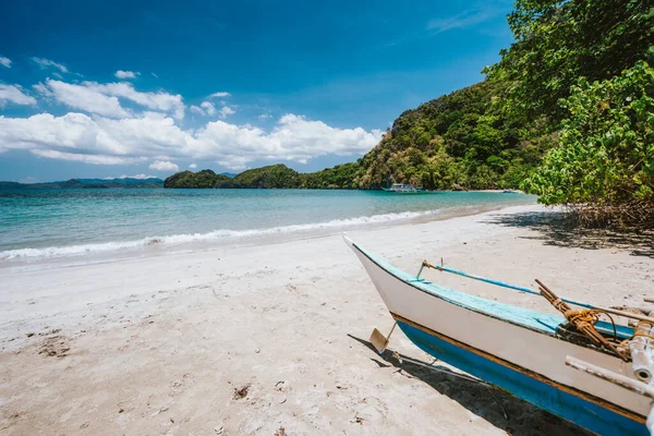 Tradiční banca loď před odlehlou tropickou pláží s exotickou modrou lagunou. El Nido, Filipíny — Stock fotografie