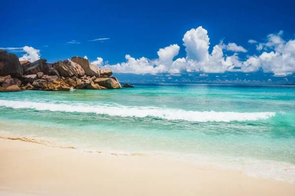 Grand Anse strand La Digue sziget Seychelles. Hullámzó hullám a homokos tengerparton, kék óceáni lagúnával. Fehér felhők a háttérben — Stock Fotó