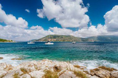 Fiskardo Yunan kasabası yakınlarındaki deniz burnu. Kefalonia, İyon adaları, Yunanistan. Akdeniz, demirli beyaz yat ve mavi gökyüzünde güzel beyaz bulutlar.